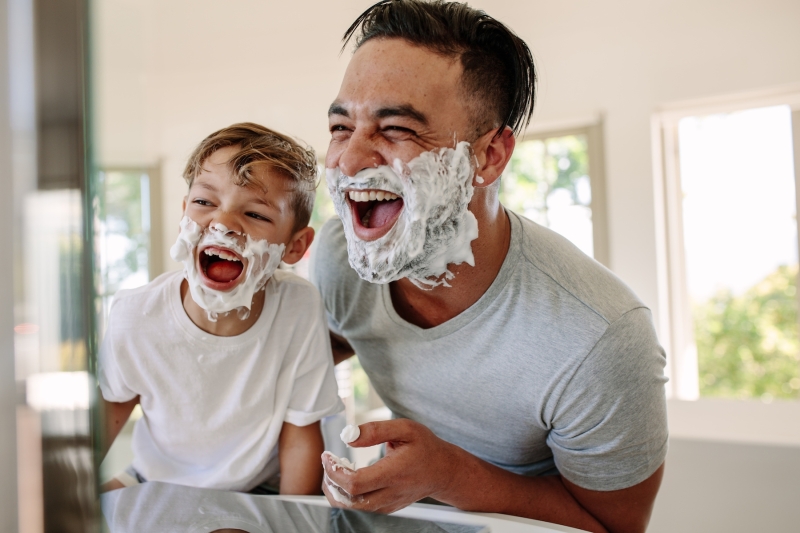 Padre jugando con su hijo mientras se afeita en el baño