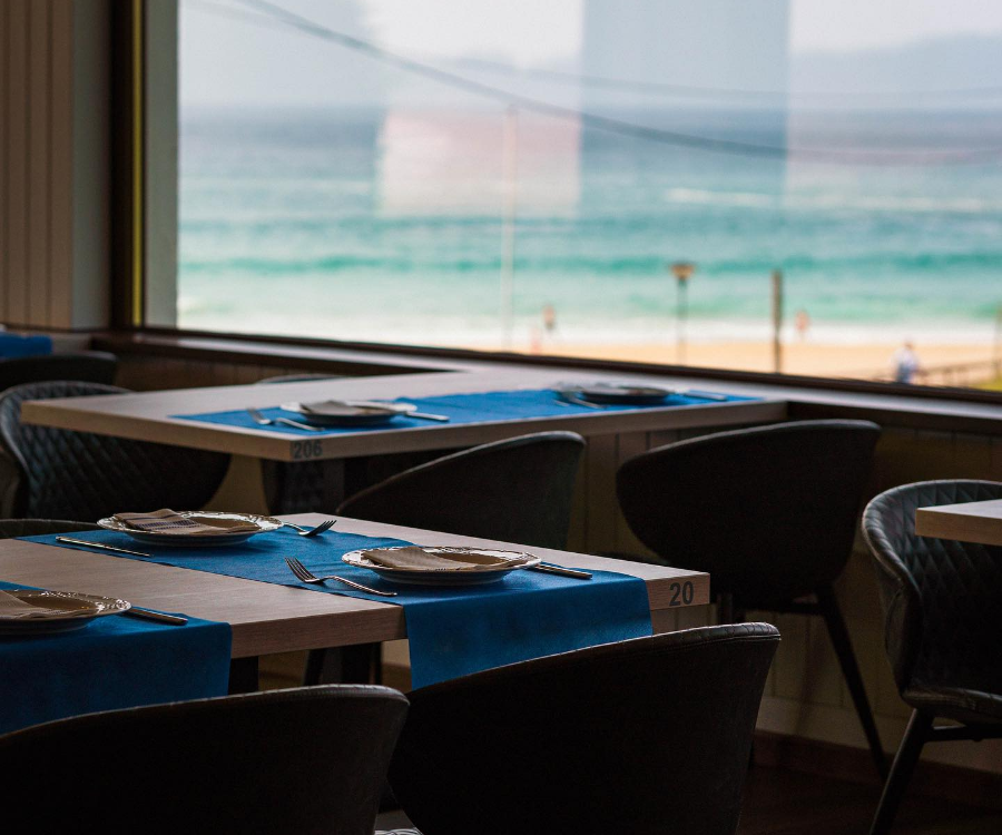 Interior del restaurante con una ventana vistas a la playa